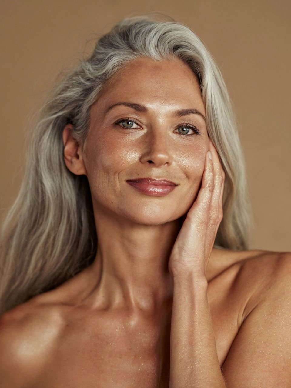 Mujer de cabello plateado con la piel luminosa y destellos dorados